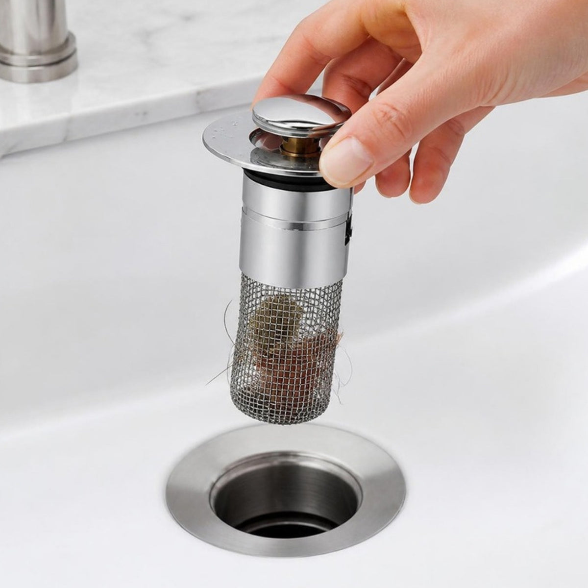 Mao retirando o filtro de inox com cabelos retidos